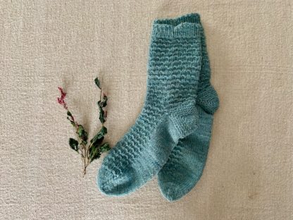 blue hand knit socks on a textured background
